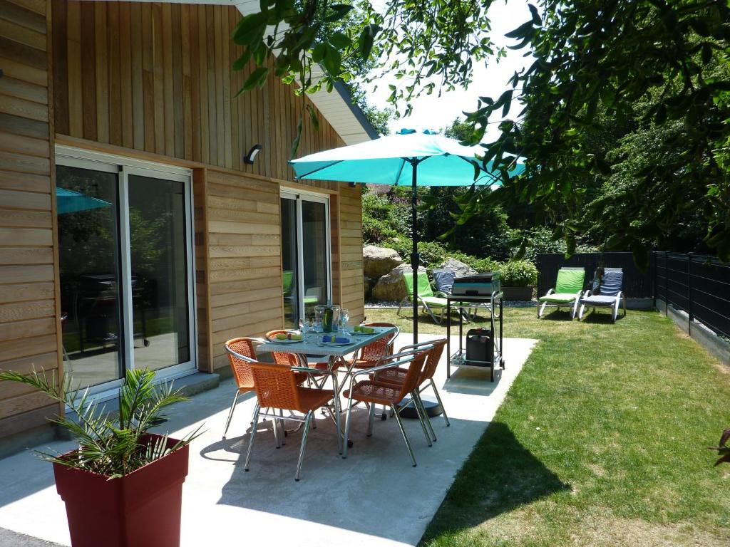 a patio with a table and chairs and an umbrella at GITE LA BAIE DES REMPARTS Les Aigrettes in Saint-Valéry-sur-Somme