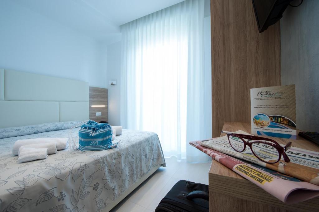 a bedroom with a bed with a pair of glasses on it at Hotel Ambasciatori in Cattolica