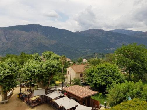 a town with trees and buildings and mountains in the background at Chez Dume in Santa-Lucia-di-Tallano