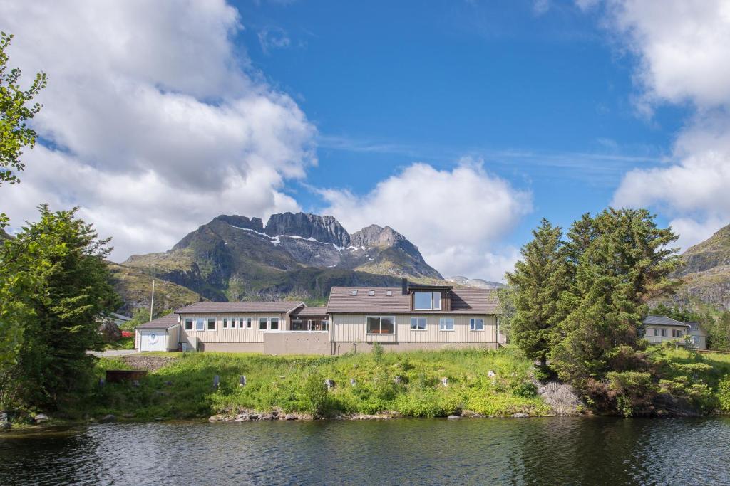 a house by the water with mountains in the background at Lofoten Planet BaseCamp in Sørvågen