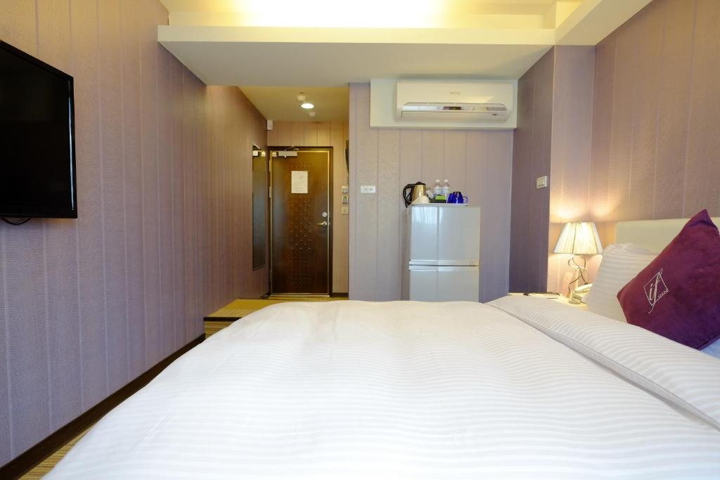 a bedroom with a large white bed and a refrigerator at 意芙旅店 Ifinn Hotel in Taipei