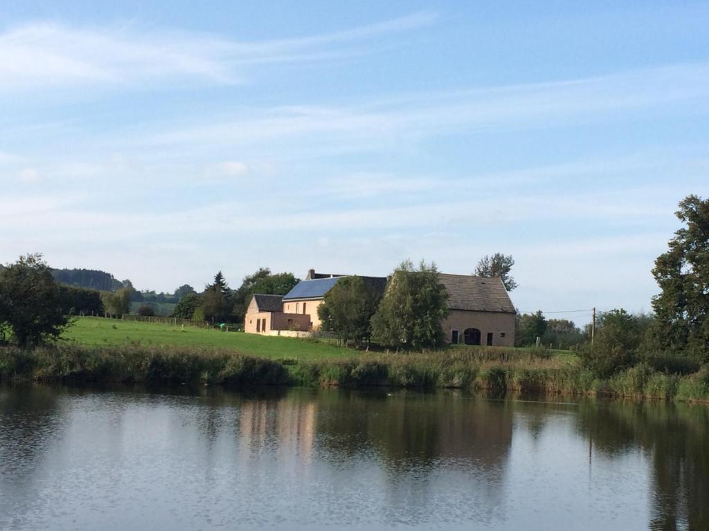 Gite des étangs à Montzen في Plombières: حضيرة بجانب نهر به منزل
