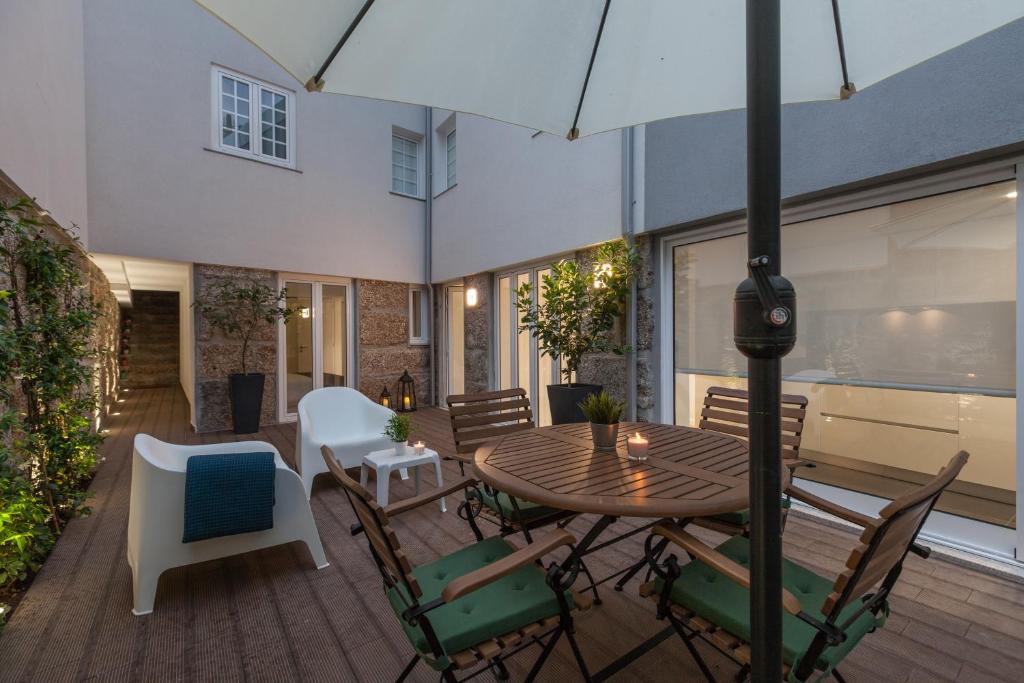 a patio with a table and chairs and an umbrella at Ana`s Houses in Guimarães