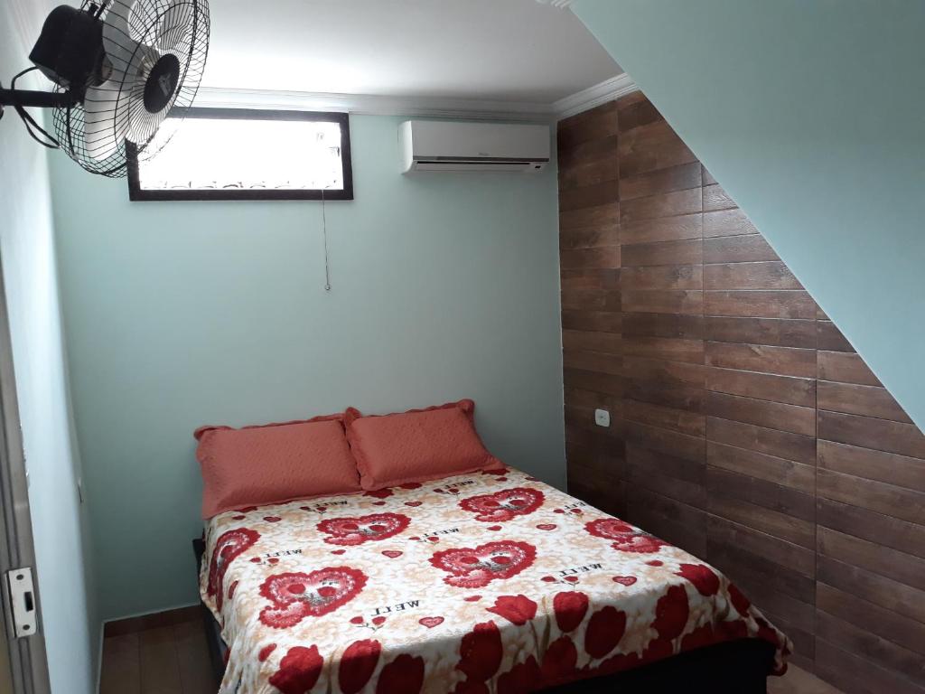 um quarto com uma cama com um edredão vermelho e branco em Casa de amigos e parentes em Eunápolis