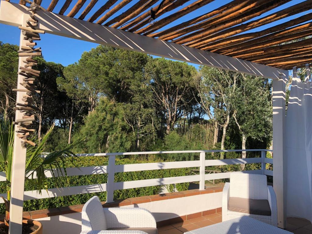 een witte pergola met witte stoelen en een hek bij Villa Emilia, Terraces & Pool in Sant Martí d’Empúries