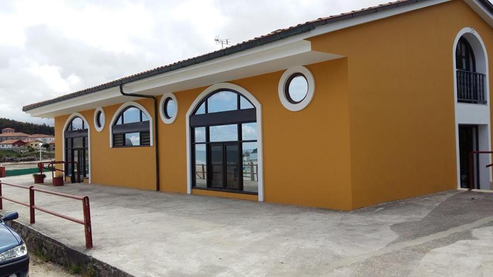 un edificio amarillo con dos ventanas y un aparcamiento en Pensión El Tabanu, en Celorio