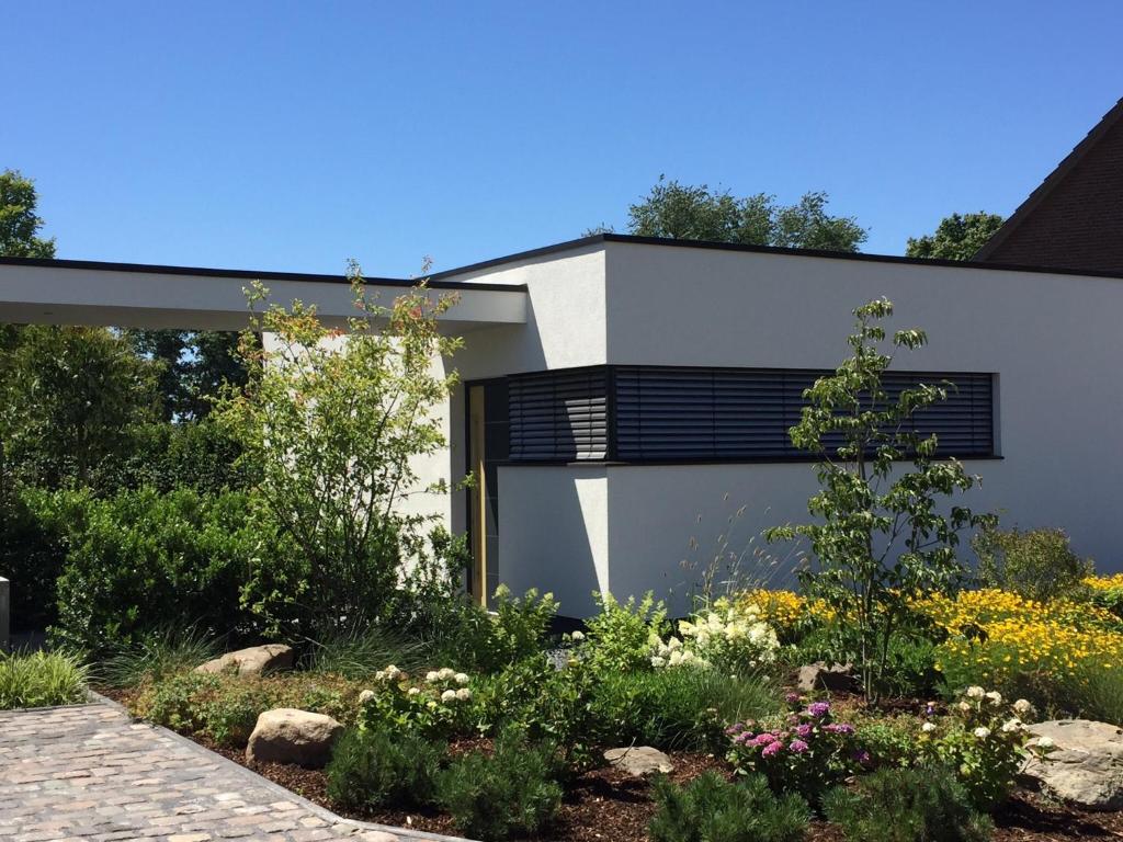 uma casa branca com janelas pretas e um jardim em das Ferienhaus Auszeit em Kranenburg