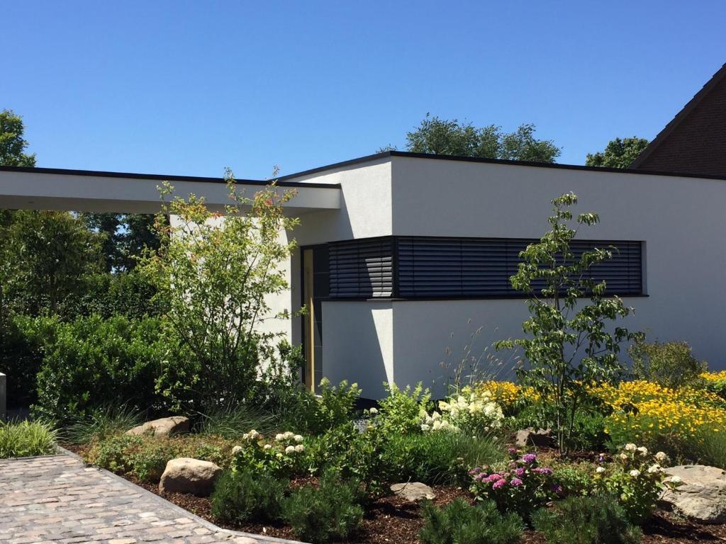 a white house with black windows and a garden at das Ferienhaus Auszeit in Kranenburg