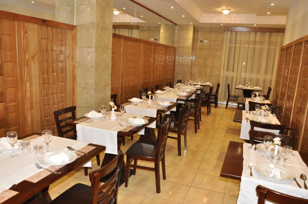 a row of tables in a restaurant with white tables and chairs at Mekelle Hotel in Mekʼelē