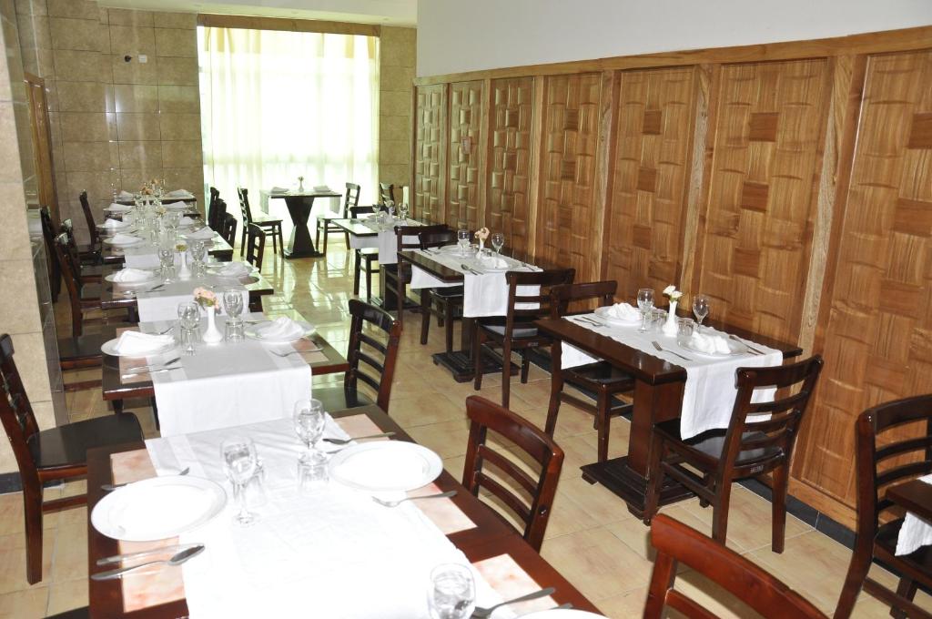 a dining room with tables and chairs with white tablecloths at Mekelle Hotel in Mekʼelē