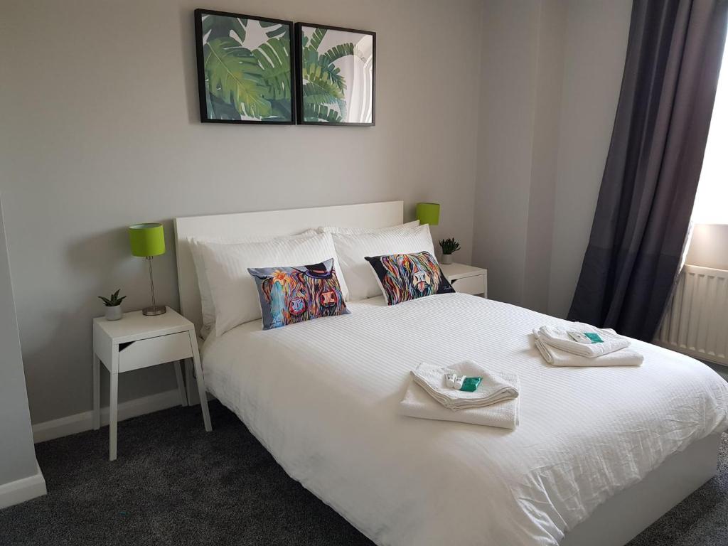 a bedroom with a white bed with two towels on it at Spire View Townhouse in Ballycastle