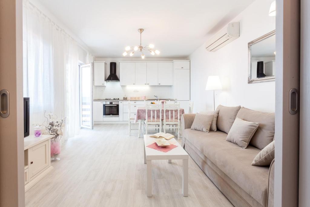 ein weißes Wohnzimmer mit einem Sofa und einem Tisch in der Unterkunft Guest House Simoni in Prigradica