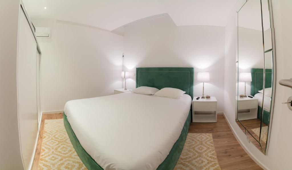 um quarto com uma grande cama branca e um espelho em Bracara Guest House "Mosteiro" - "Falperra" em Braga