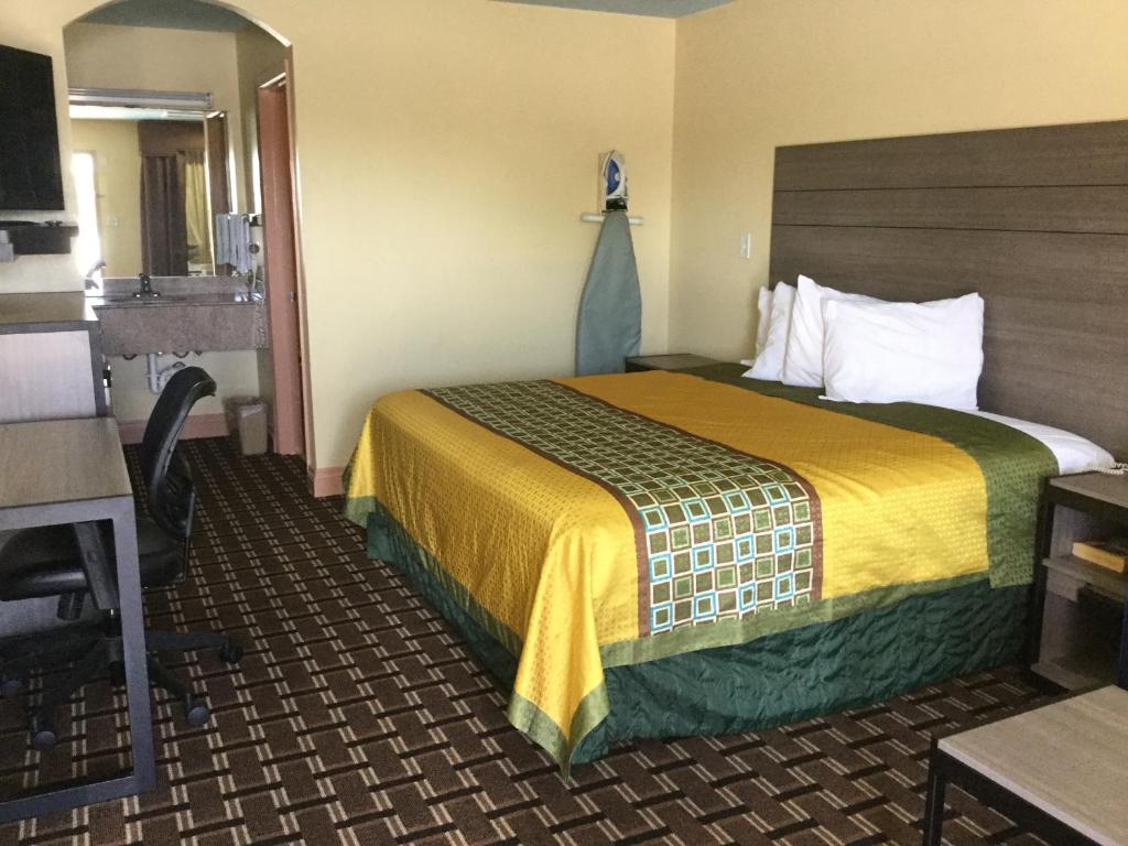 a hotel room with a bed with a yellow blanket at Luxury Inn and Suites Seaworld in San Antonio
