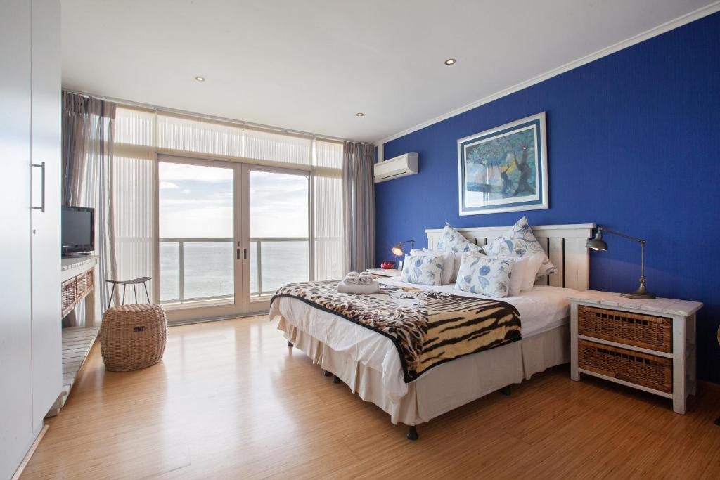 - une chambre bleue avec un lit et une grande fenêtre dans l'établissement New Cumberland 501 by CTHA, au Cap