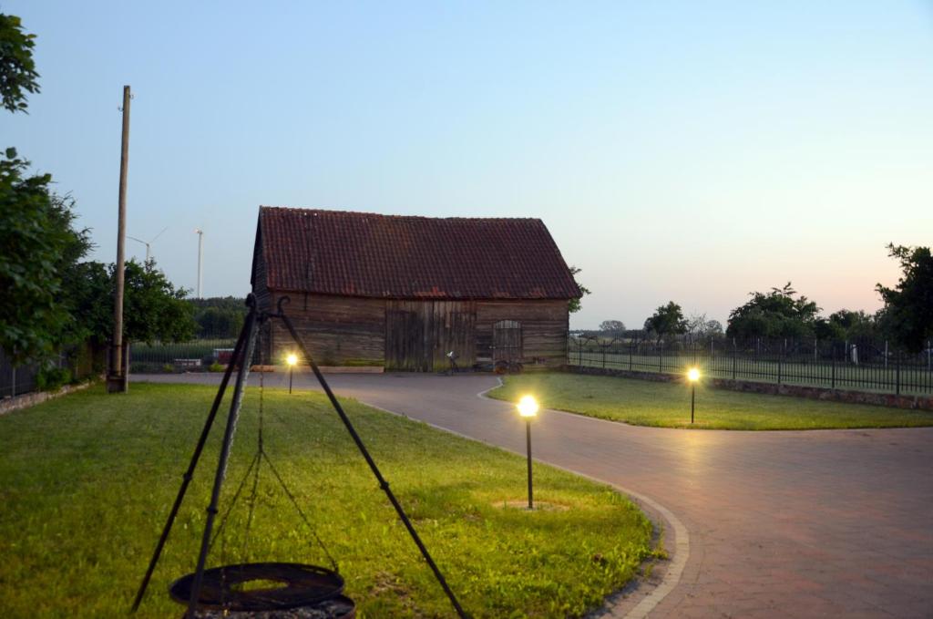 a wooden barn with lights in front of it at Za Stodołą in Wydminy