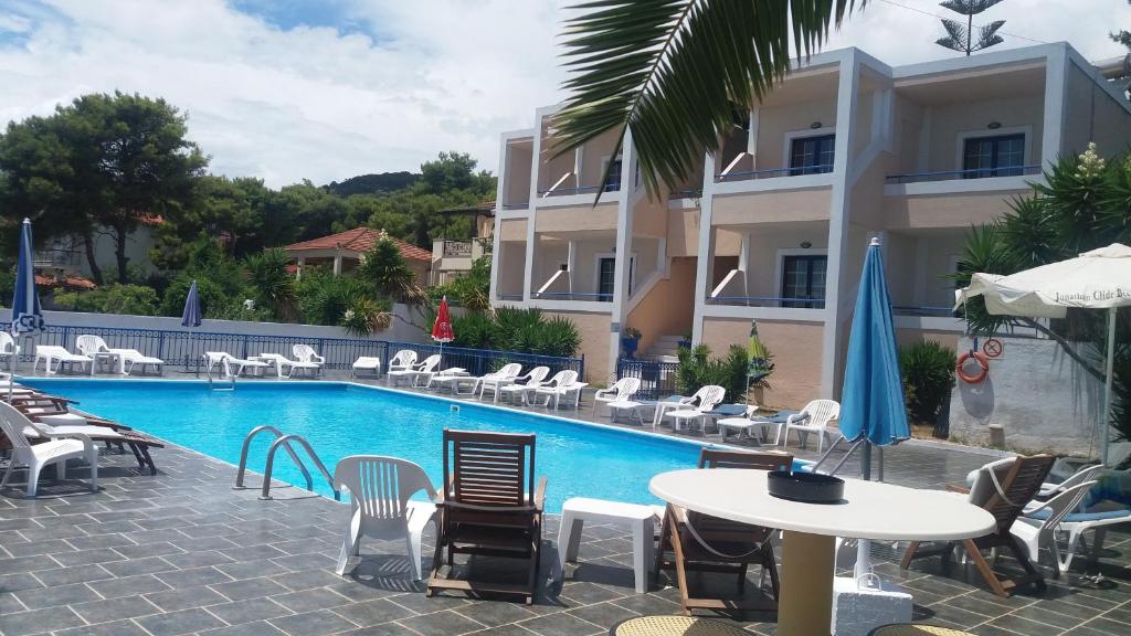 um hotel com piscina, mesas e cadeiras em Anna Studios em Agia Marina