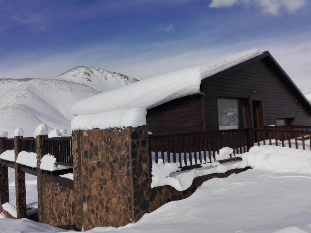 a house covered in snow in front of a fence at Villa Montaña in Las Lenas