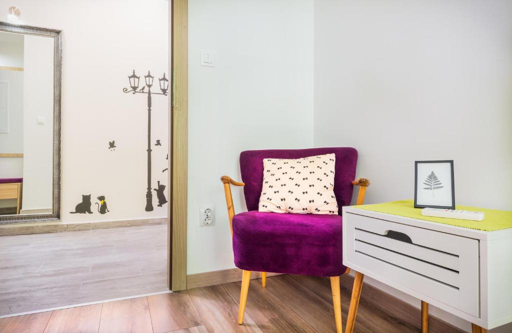 una silla púrpura junto a un tocador y un espejo en Apartman Nicoletta en Split