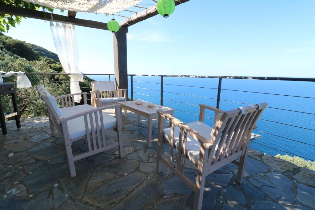 a table and chairs on a patio overlooking the water at Fakistra's Blue House in Tsagarada