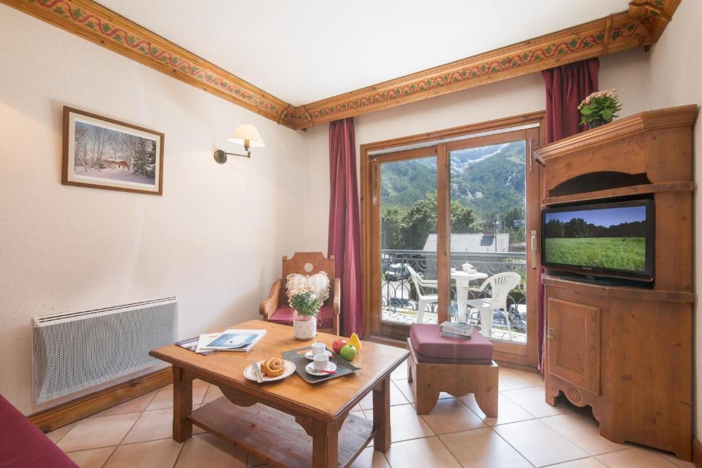 een woonkamer met een tafel en een televisie bij Résidance Le Cristal - Grands Montets 11 - Happy Rentals in Chamonix-Mont-Blanc