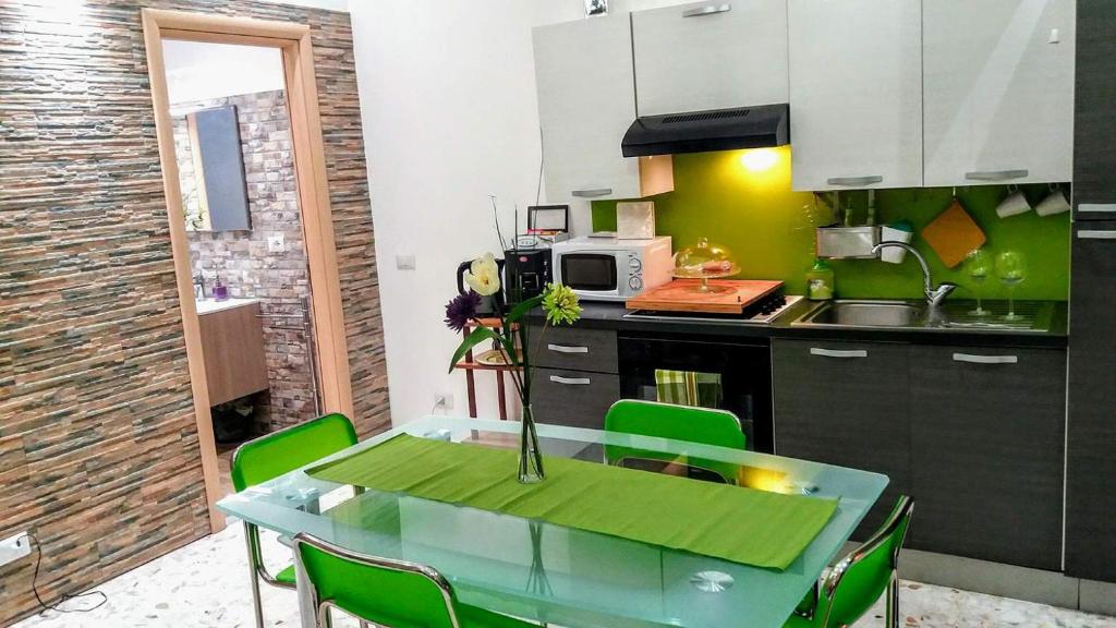 une cuisine avec une table et des chaises vertes dans l'établissement Corte Degli Aranci House, à Paterno