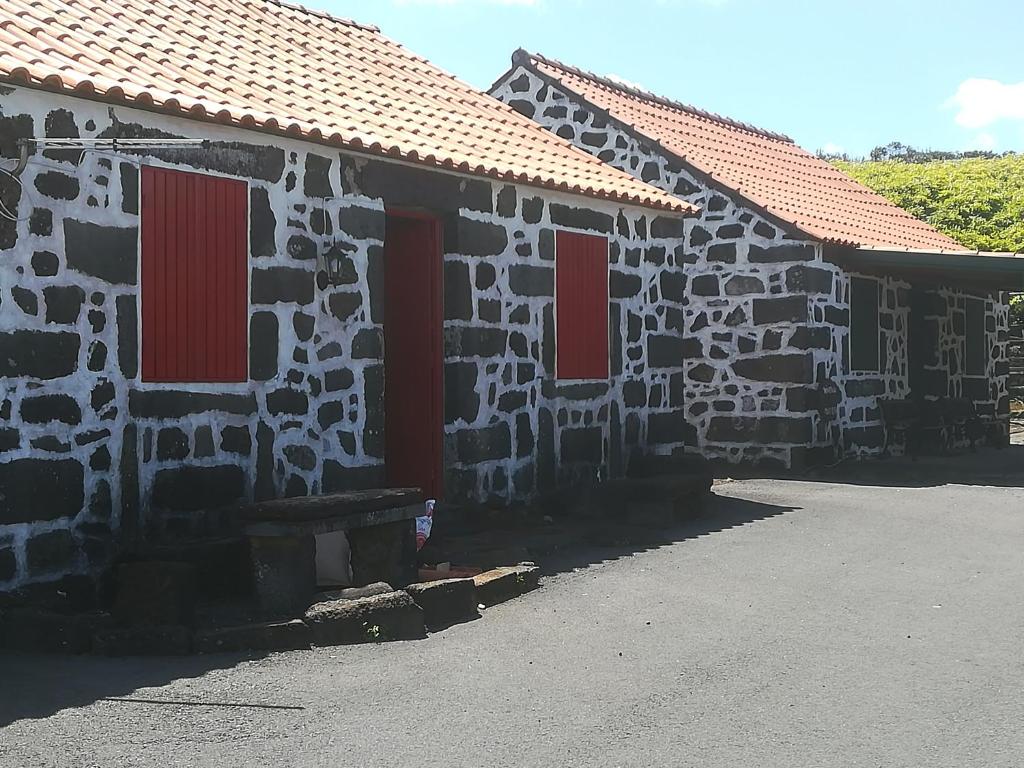 a stone building with red doors and a bench at Adega dos Virgilios in Madalena