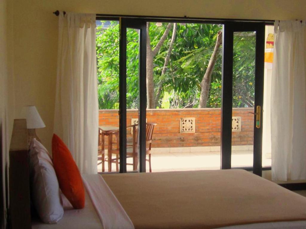 a bedroom with a bed and a view of a patio at Purnama di Bisma in Ubud