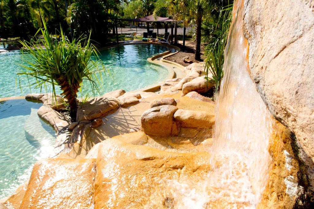 
a large pool of water surrounded by rocks and trees at Cooinda Lodge Kakadu in Jabiru
