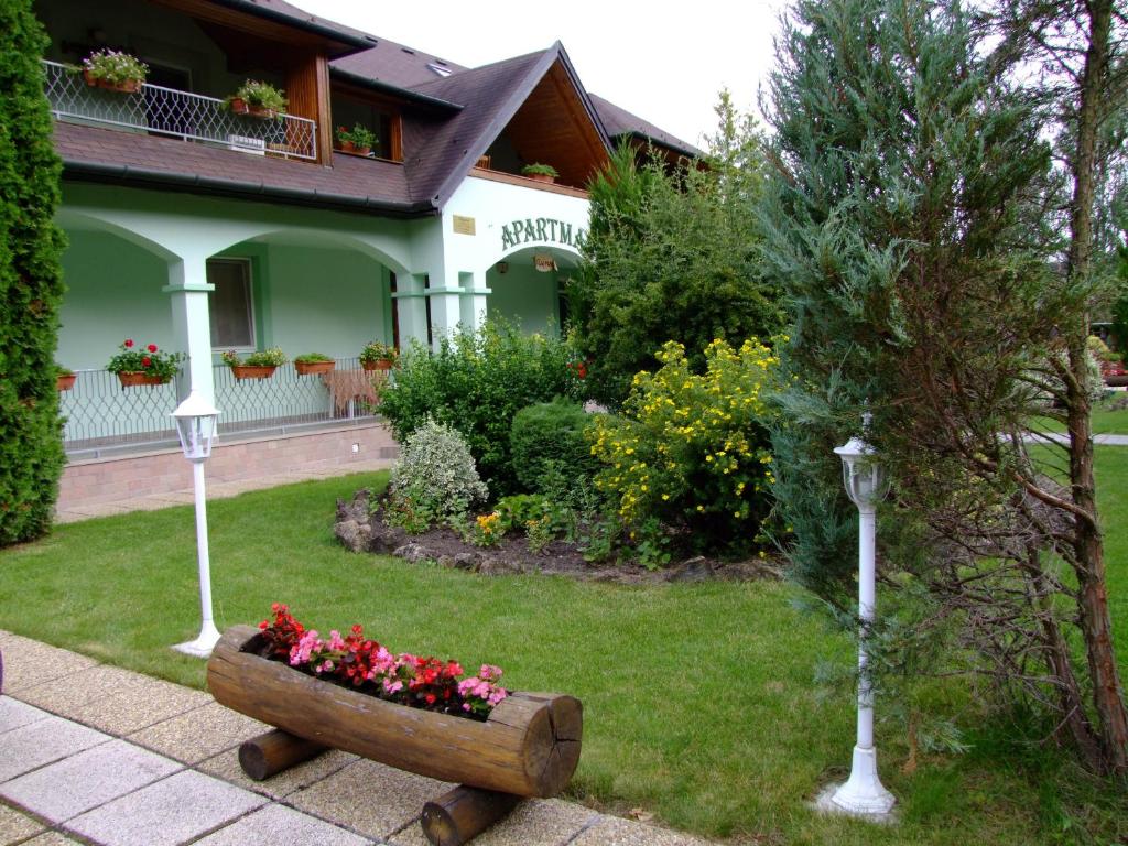 a house with a flower bed in the yard at Rajna Apartmanház in Bogács