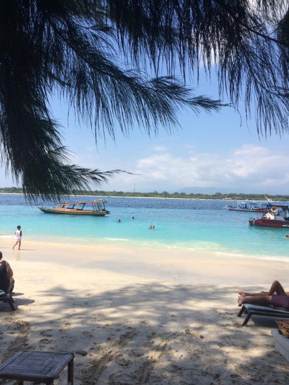 a beach with boats and people in the water at Gili Turtle Beach Resort in Gili Trawangan