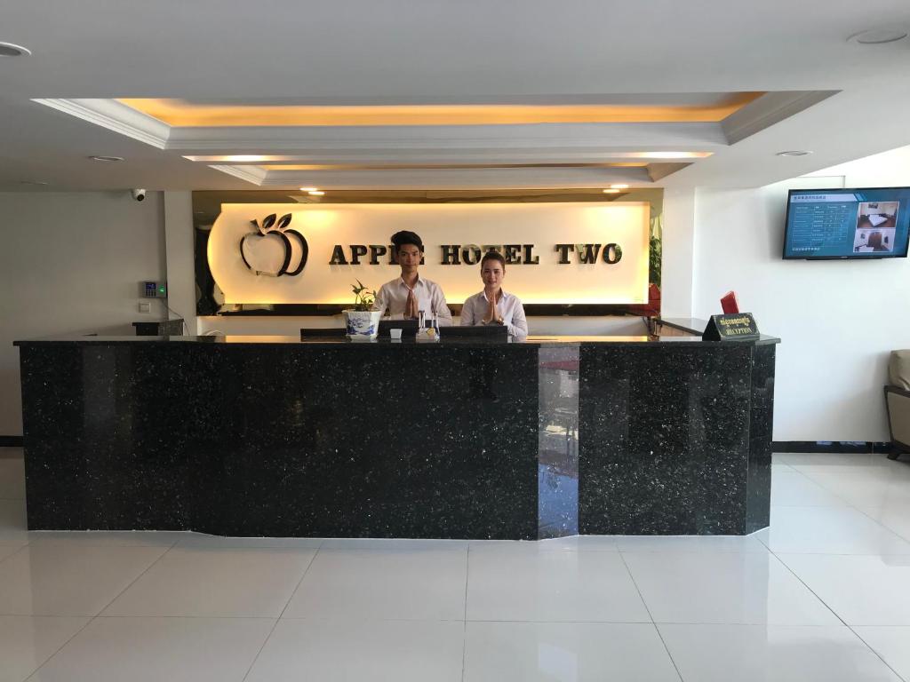 two people standing at a counter in a restaurant at Apple Hotel Two - Near Phnom Penh Airport in Phnom Penh