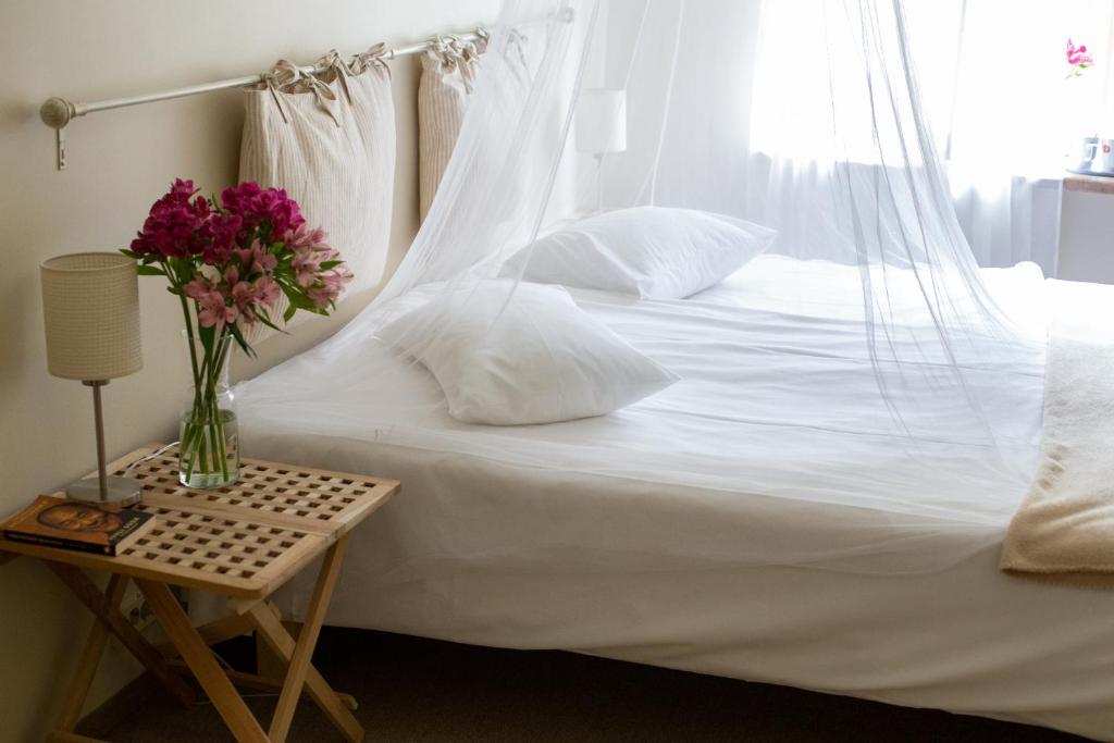 ein weißes Bett mit einer Blumenvase auf dem Tisch in der Unterkunft Kuursaal Guesthouse in Kuressaare