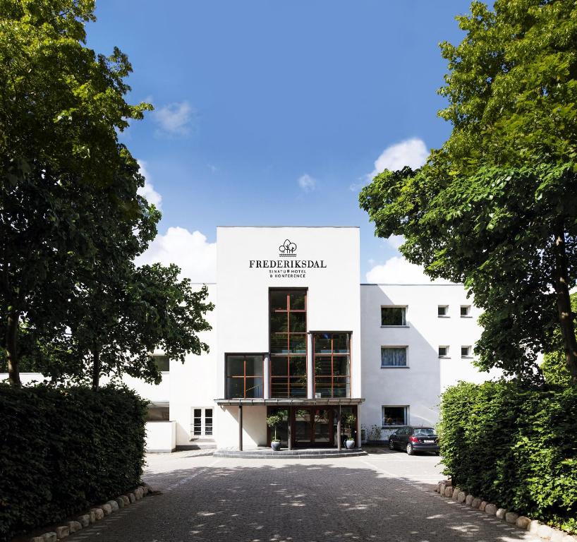 a white building with a sign on the front of it at Frederiksdal Sinatur Hotel & Konference in Kongens Lyngby