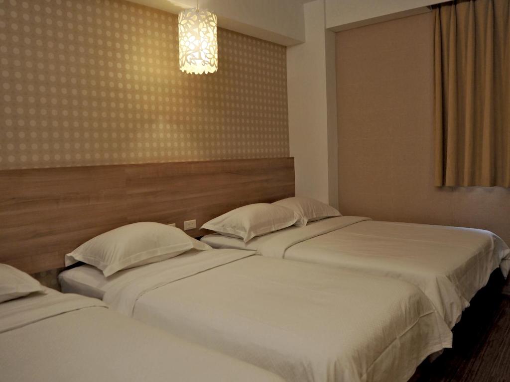 two beds in a hotel room with at The Riverside Hotel Hengchun in Hengchun South Gate