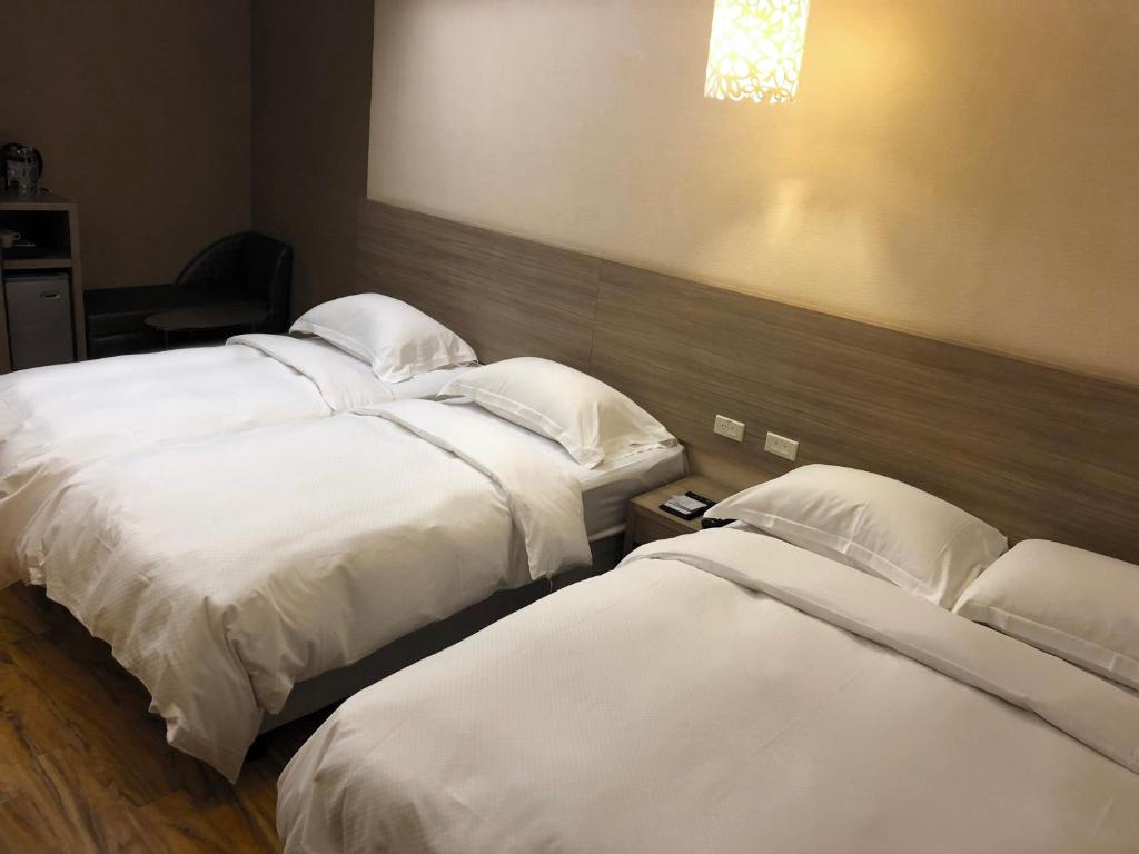 a hotel room with two beds with white sheets at The Riverside Hotel Hengchun in Hengchun South Gate