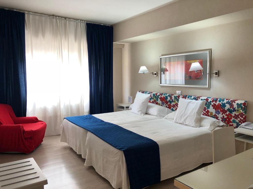 una habitación de hotel con una cama grande y una silla roja en Hotel Virrey en Arnedo