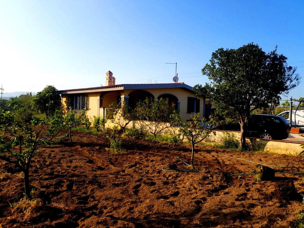 a house in a field with trees in front of it at Villetta Su Barrali in Orosei