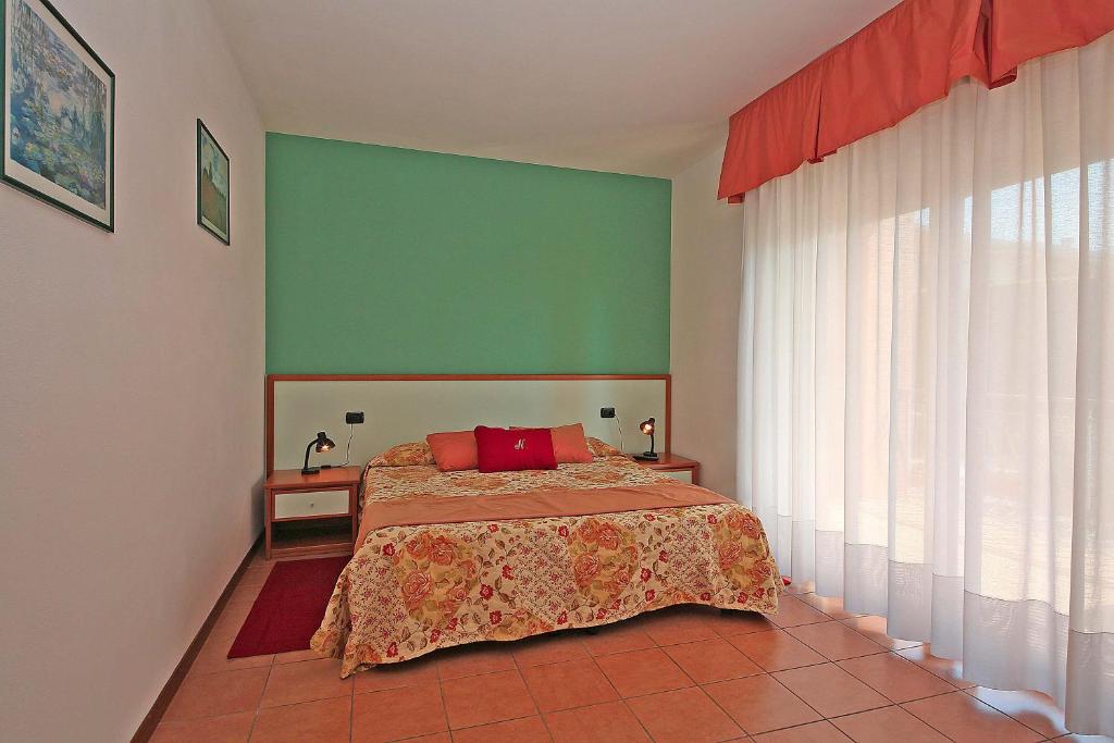 een slaapkamer met een bed en een groene muur bij Nettuno Residence Hotel in Peschiera del Garda