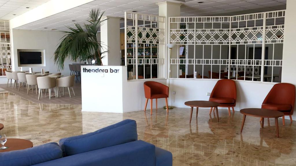 a waiting room with a blue couch and red chairs at Marina Hotel in Ayia Napa