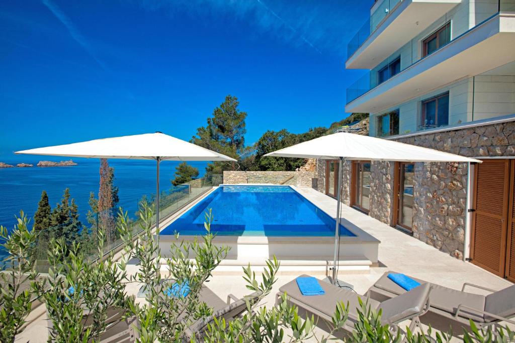 a villa with a swimming pool and two umbrellas at Villa Malo More in Dubrovnik