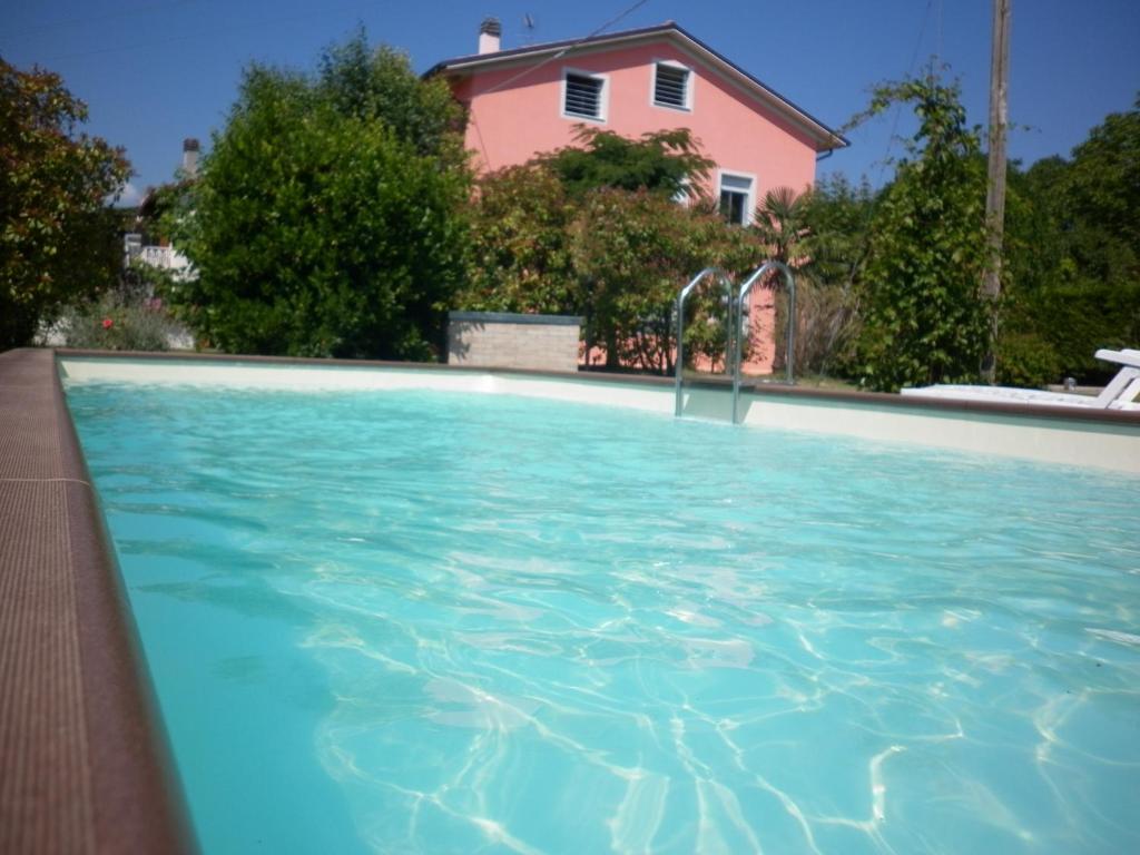 a swimming pool in front of a pink house at Villa Jolanda in San Lorenzo in Campo