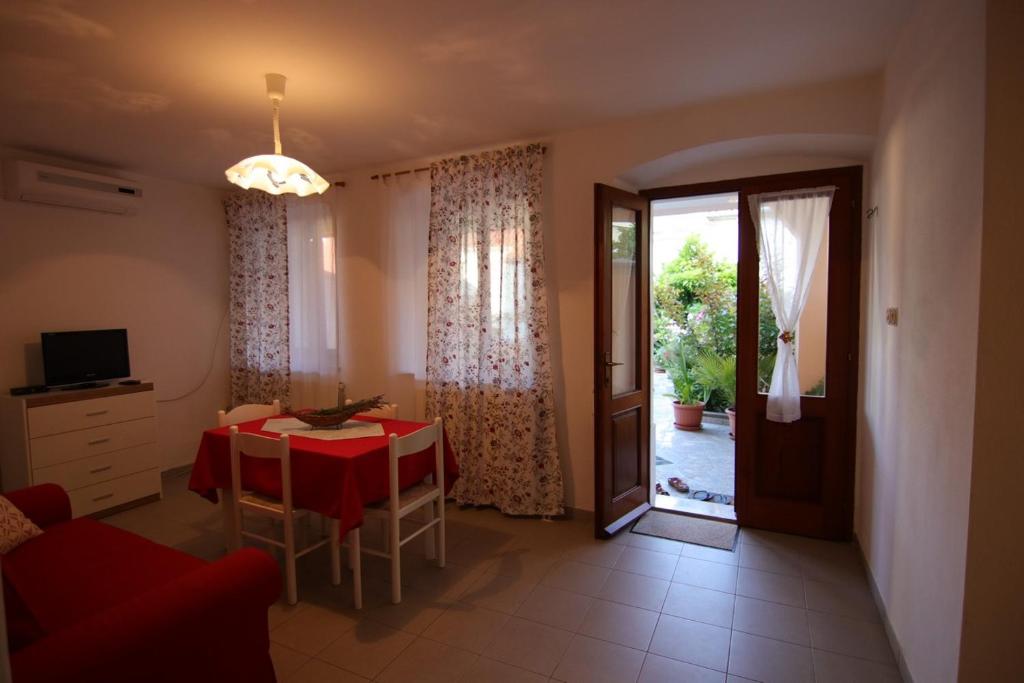 un salon avec une table et un tissu de table rouge dans l'établissement App with a lovely patio, à Mali Lošinj