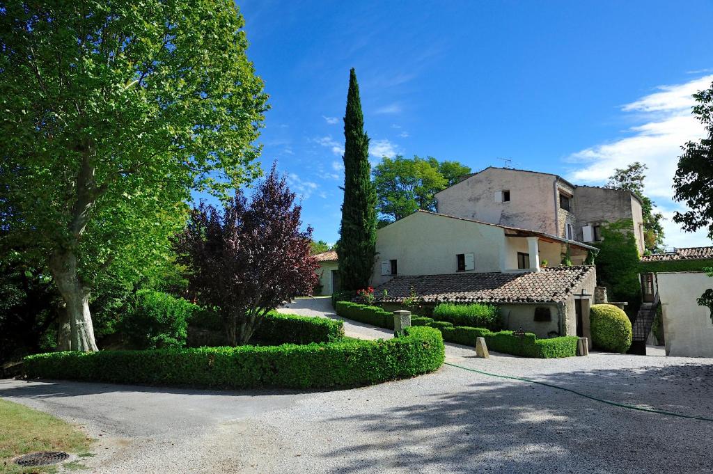 une maison avec des arbres et des buissons dans une allée dans l'établissement Charembeau, à Forcalquier