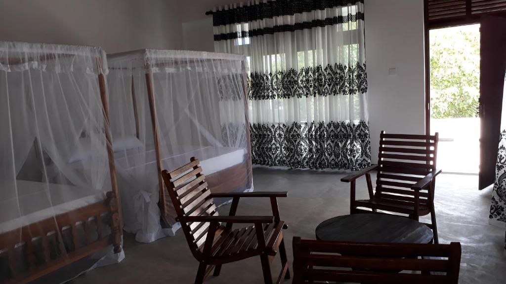 two chairs and a table in a room with curtains at Silance Garden in Tangalle