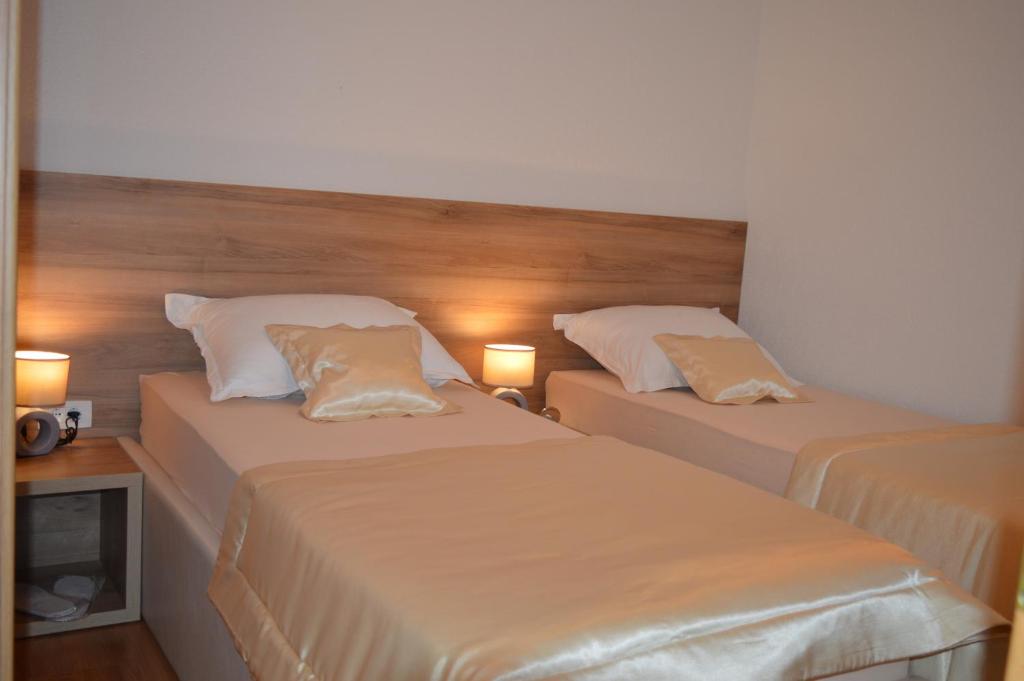 two beds in a hotel room with two lamps at Blue Lake Luxury Rooms in Grabovica