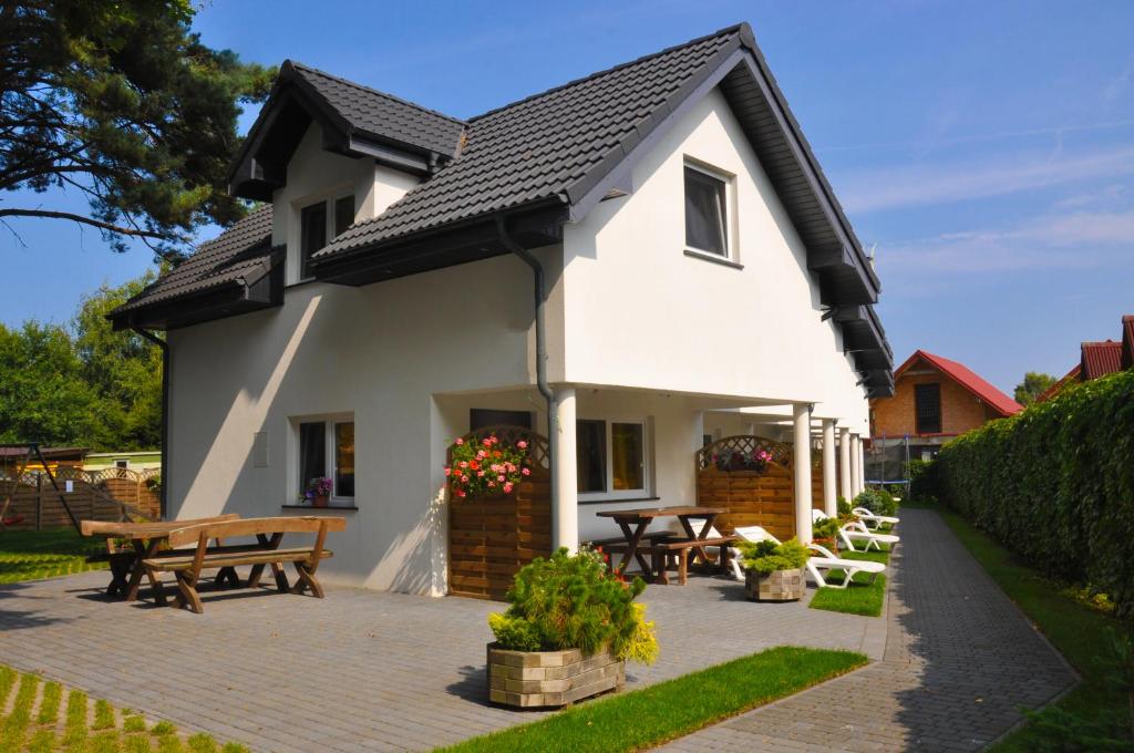 a white house with picnic tables and benches at Ferienhaus Holiday Home Domki RAJ in Jarosławiec