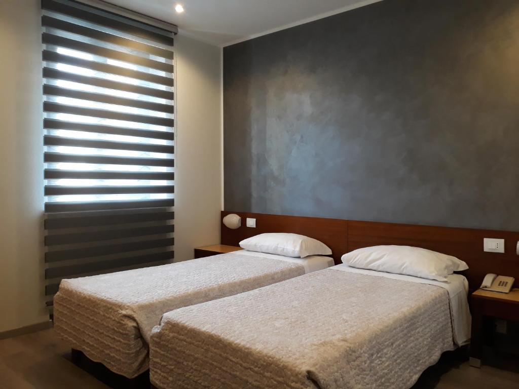 Hotel San Giorgio في أوديني: غرفة نوم بسريرين ونافذة