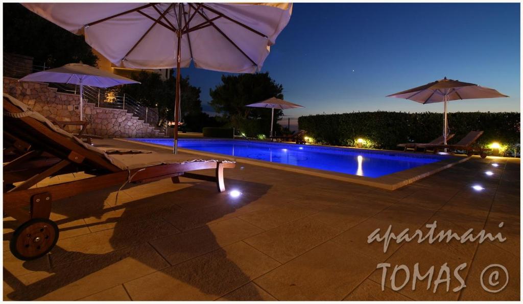 a swimming pool with umbrellas and a swimming pool at Apartments Tomas in Primošten