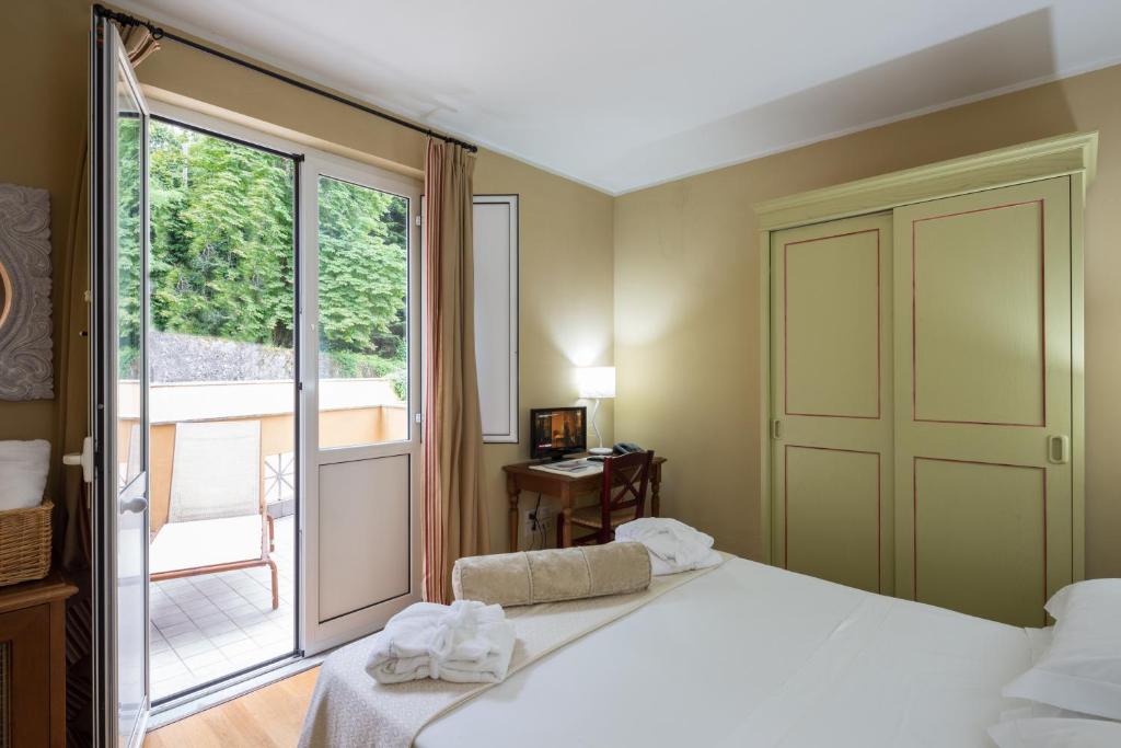 ein Schlafzimmer mit einem Bett und einem großen Fenster in der Unterkunft Hotel & Terme Bagni di Lucca in Bagni di Lucca